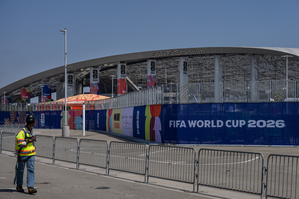 A worker walks past temporary fencing with FIFA World Cup 2026 signage outside SoFi Stadium, Friday, June 5, 2026, in Inglewood, Calif. 