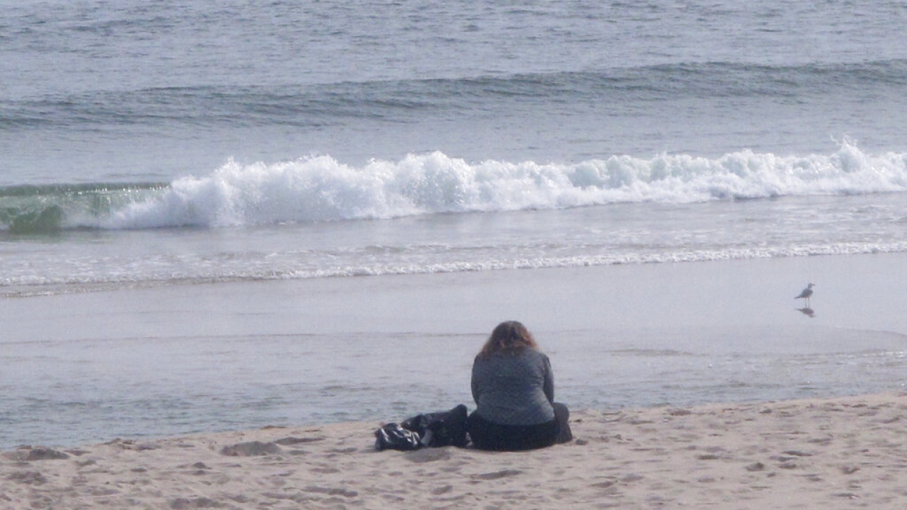 A surfboard lies on the sand on the sand at a beach.
