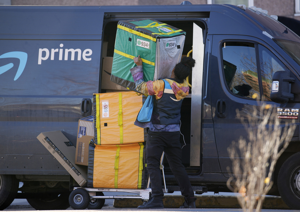 An Amazon Prime delivery person lifts packages while making a stop at a high-rise apartment building, Nov. 28, 2023, in Denver. 