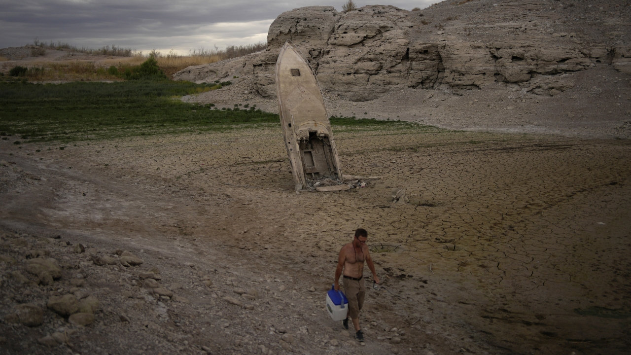 Man walks by a formerly sunken boat at Lake Mead.