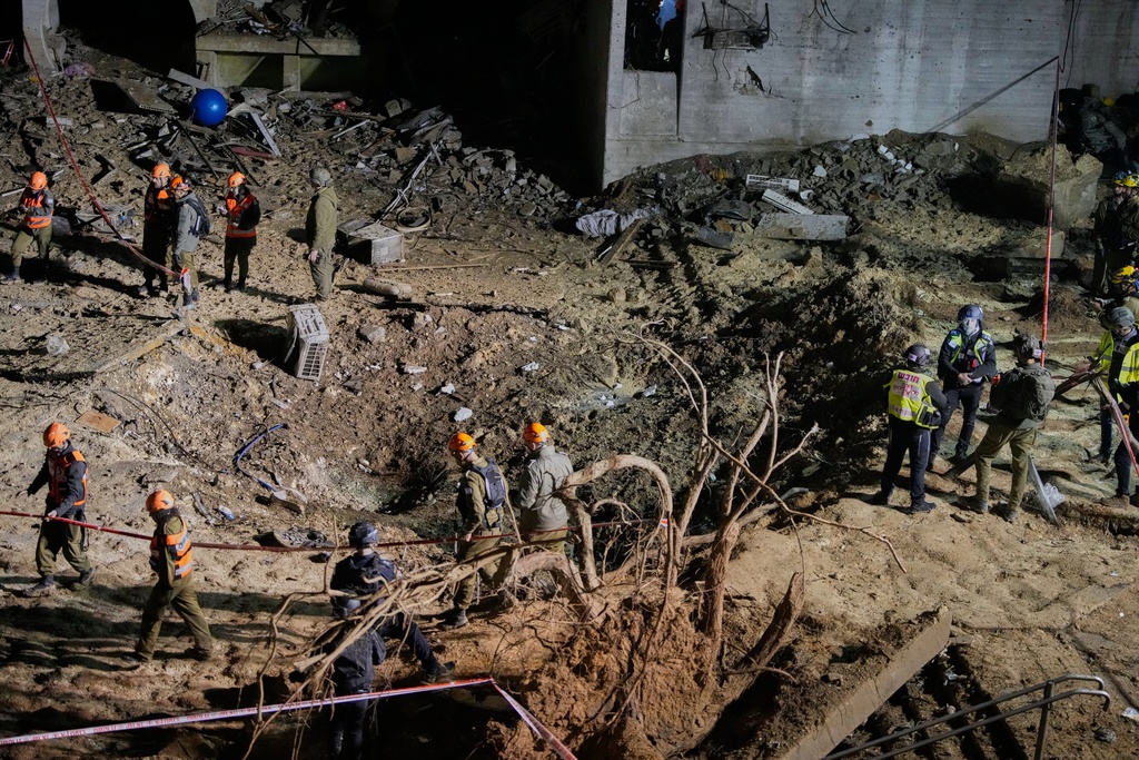 Israeli security forces and rescue teams inspect the crater left by an Iranian missile in Arad, southern Israel.