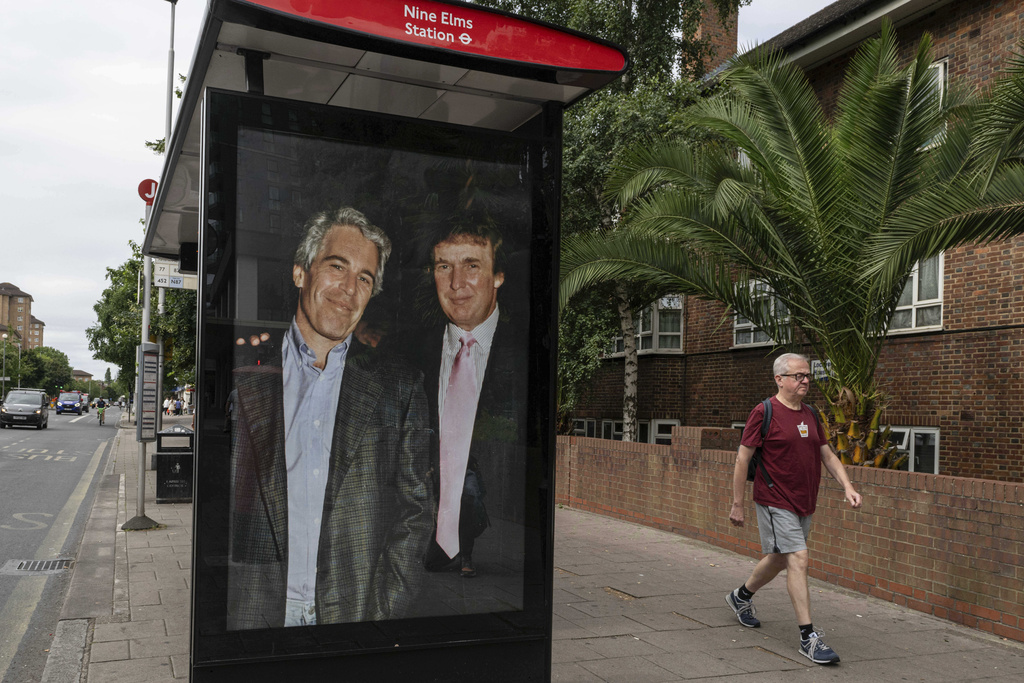 Commuters walk past a bus stop in London where activists put up a poster showing President Donald Trump and Jeffrey Epstein.