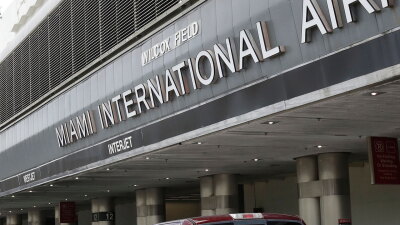 FILE - Vehicles drive past the entrance to Miami International Airport in Miami on Tuesday, May 12, 2020.