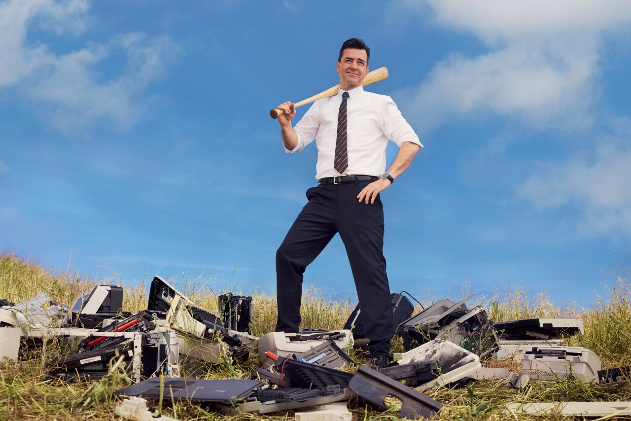 A man with a bat over printers.