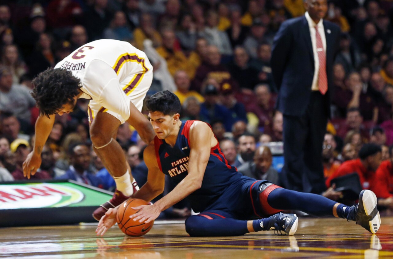 FAU Owls basketball player William Pfister battles for loose ball vs. Minnesota Golden Gophers