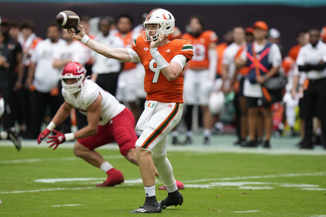 Miami Hurricanes QB Tyler Van Dyke passes vs. Louisville Cardinals defensive lineman Mason Reiger in first half, Nov. 18, 2023
