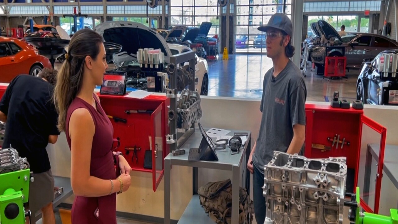 Students watch as an instructor traces a full 720-degree crank cycle on a training engine’s timing wheel.