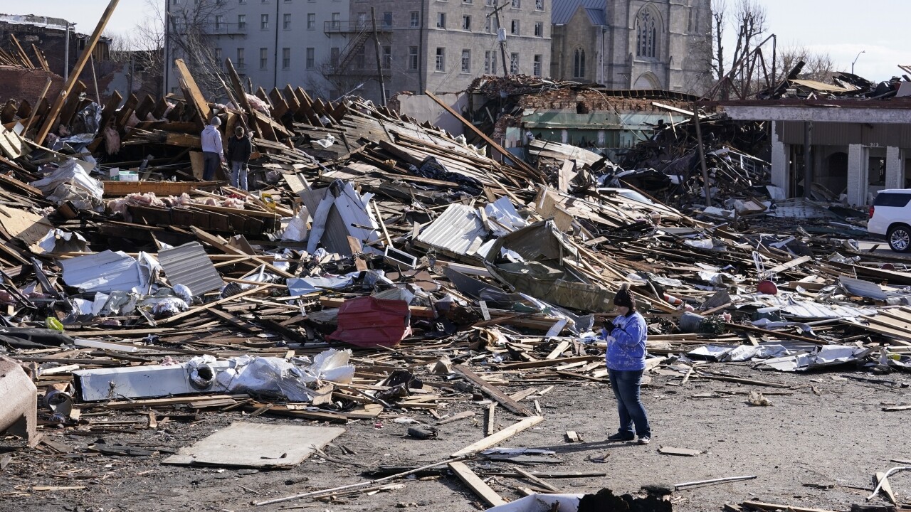 A person stands near debris cause by tornado damage in Mayfield, Ky., on Saturday, Dec. 11, 2021.