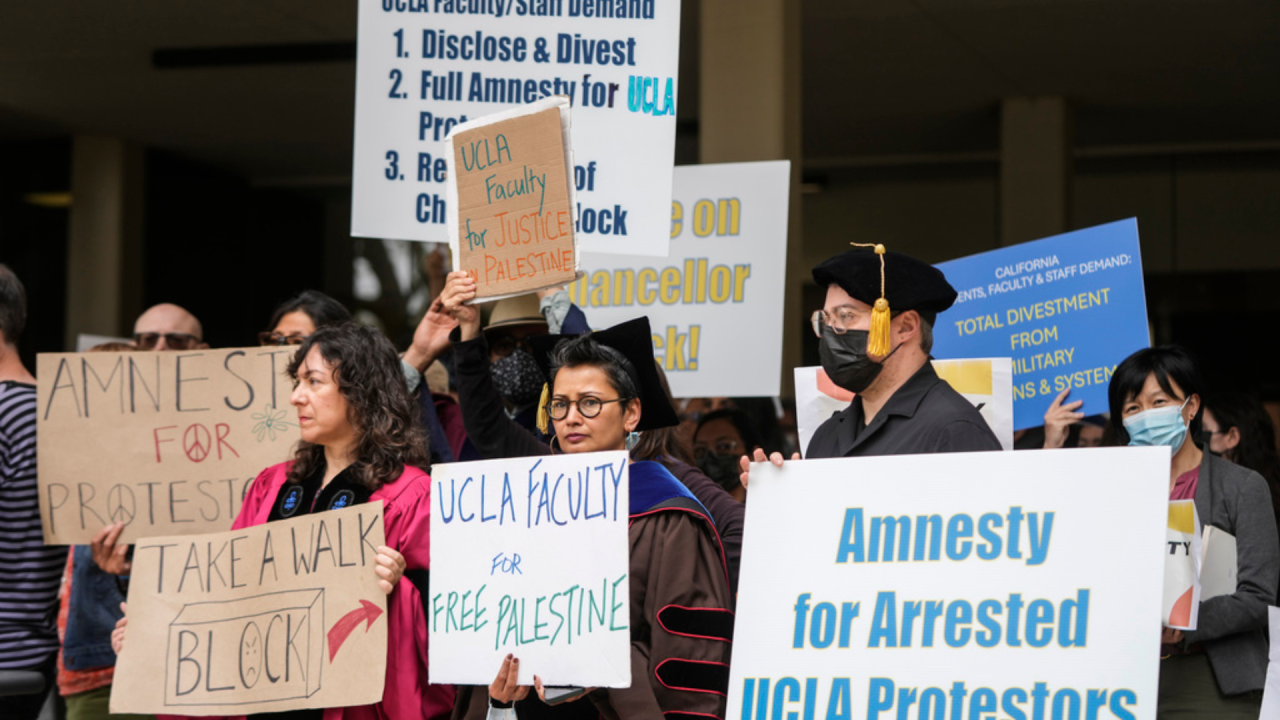 UCLA faculty and staff members hold signs during a news conference at UCLA