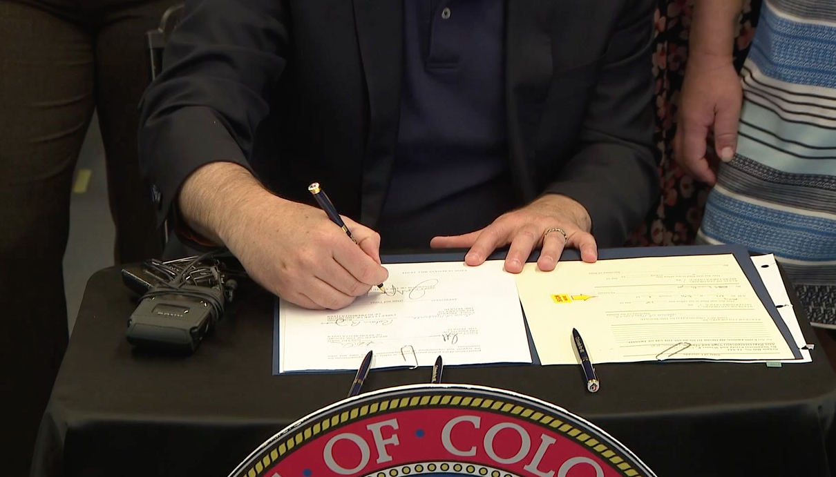polis signs bill on train.png