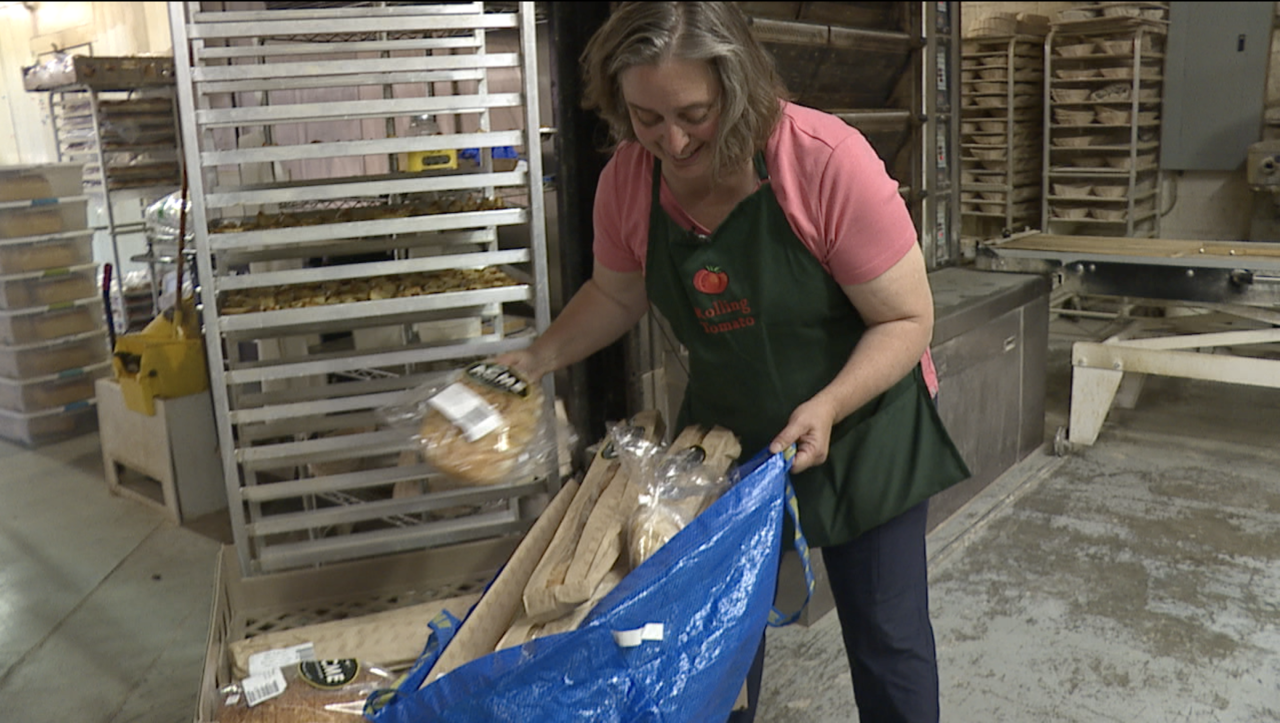 Rolling Tomato executive director Julie D'Agostino picks up a pallet of leftover bread from Acme Bakeshop.