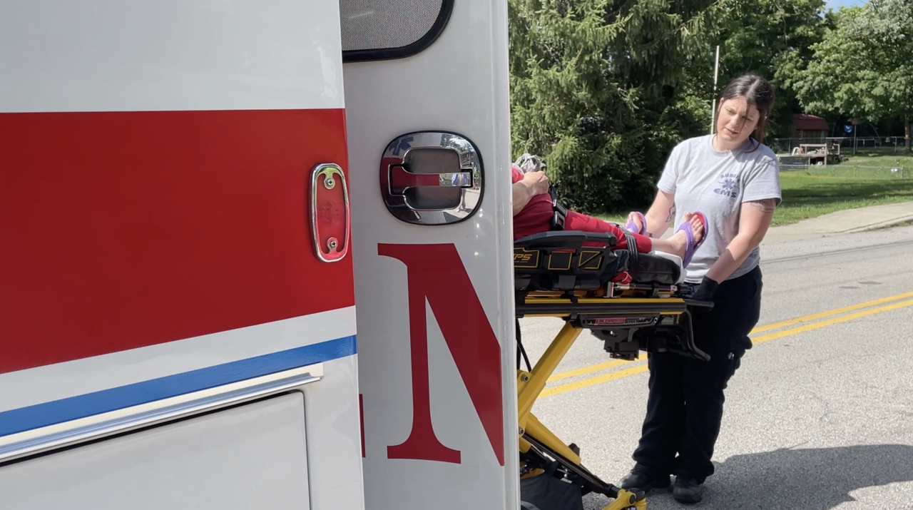 An Aurora EMS squad helps a patient get on an ambulance