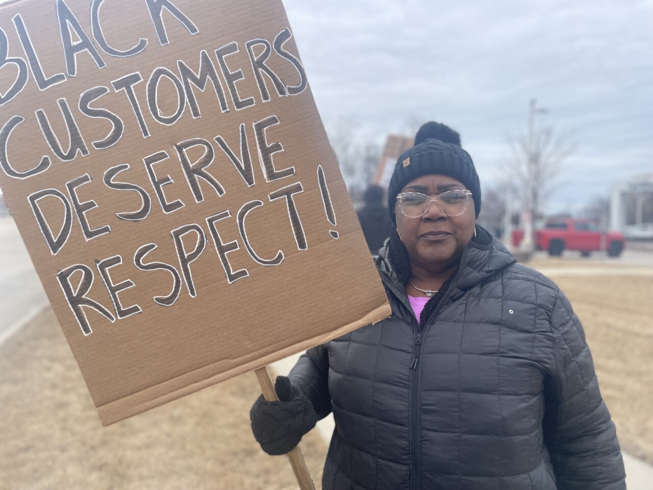 Barbara Jones holds sign that reads "black customers deserve respect"