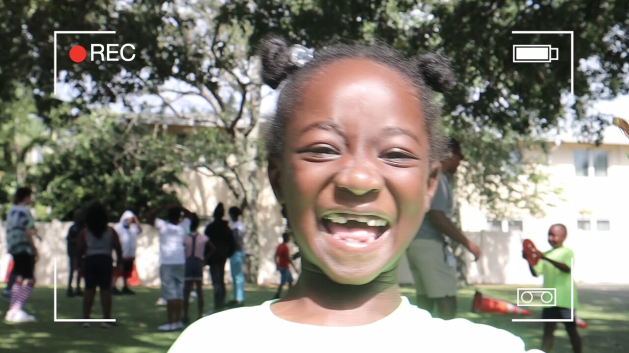A child plays with WPTV's camera during Adopt-A-Family's Project Grow summer camp in Lake Worth Beach on June 17, 2022.jpg