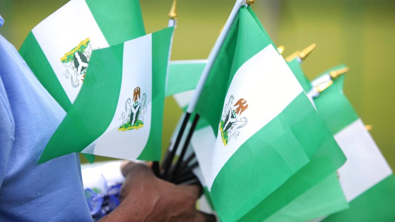 A person holding Nigerian national flags.