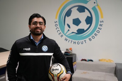 Warshan Hussin in front of the Soccer Without Borders logo