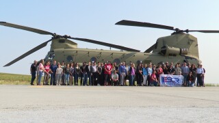 Participants line up for a photo in front of a Chinook