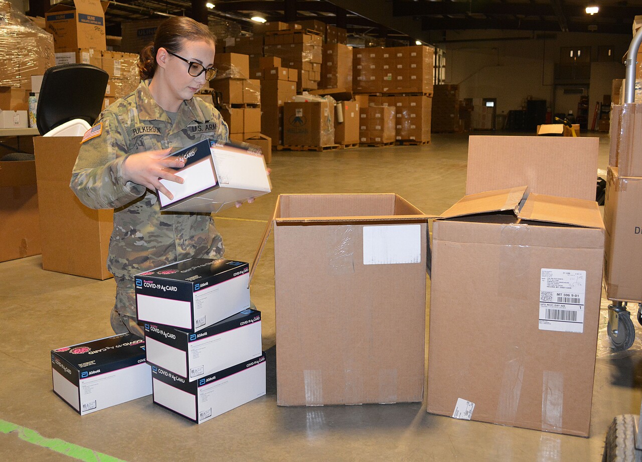 SPC Patricia Fulkerson preparing a box of rapid antigen tests kits for shipping at the state warehouse.