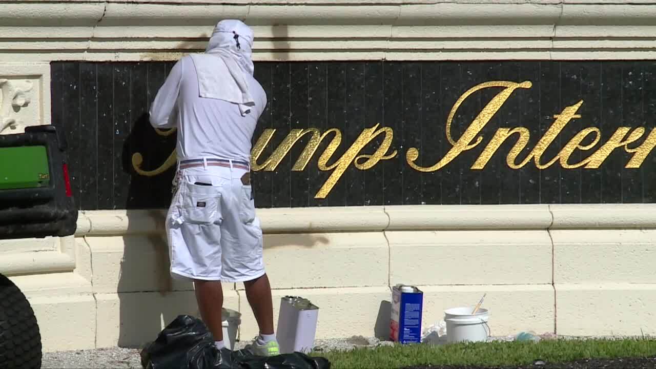 Worker painting over graffiti on Trump International Golf Club sign, Aug. 11, 2023