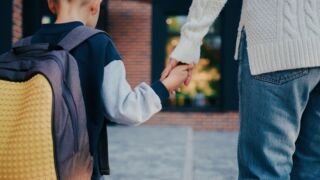 Stock image of a young boy and his mother holding hands.
