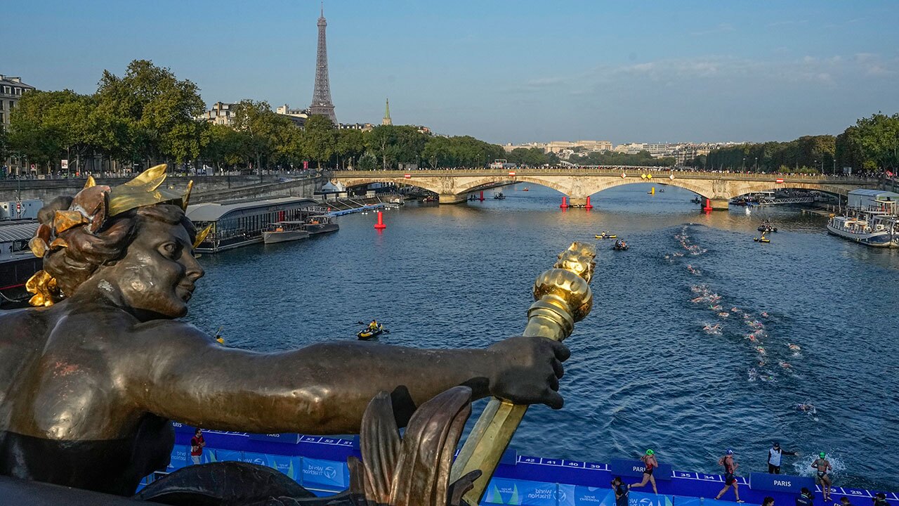 FILE - Athletes dive and swim in the Seine River from the Alexander III bridge on the first leg of the women's triathlon test event for the Olympics Games in Paris, Aug. 17, 2023. Water in the Seine River had unsafe elevated levels of E. coli less than two months before swimming competitions are scheduled to take place in it during the Paris Olympics, according to test results published Friday, June 14, 2024.