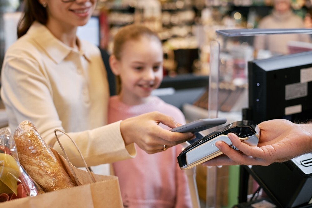 Smiling,Woman,Making,Payment,At,Store,Counter,With,Child,Happily
