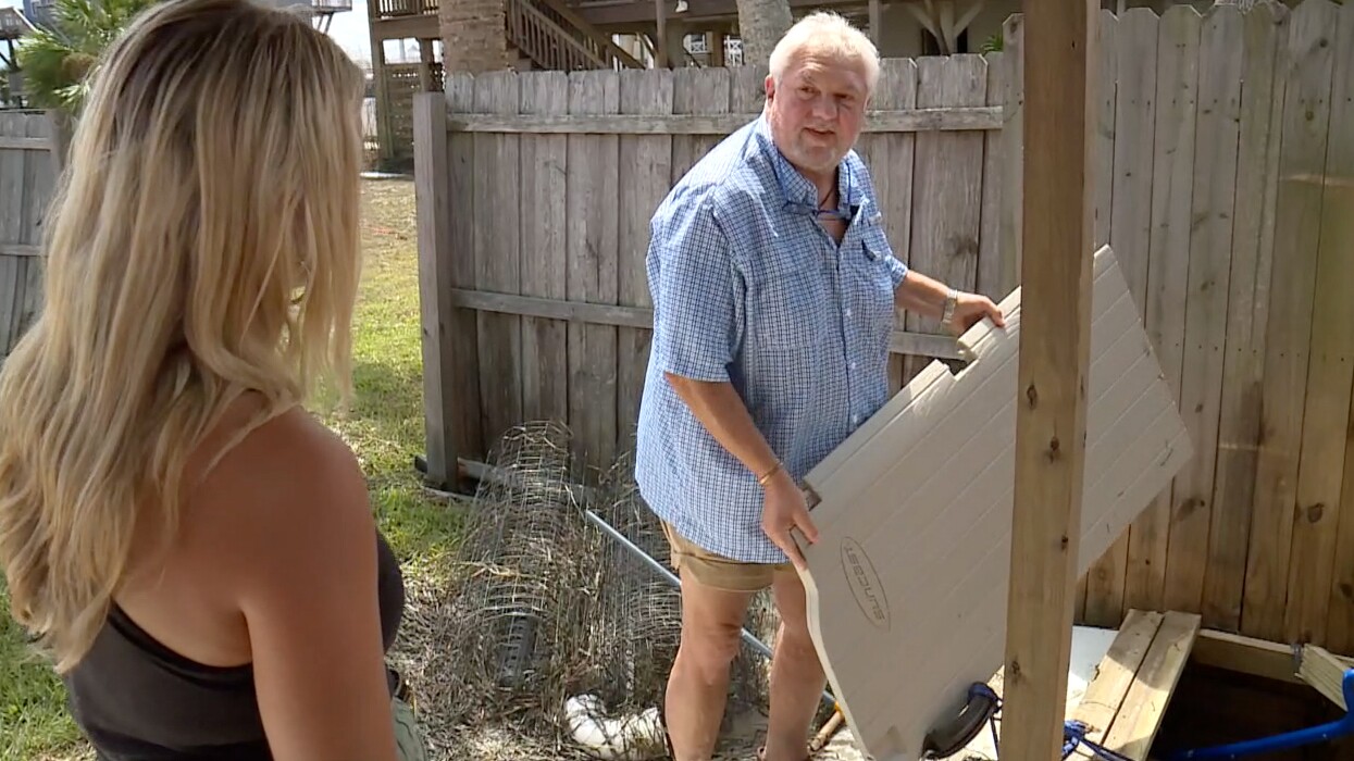 Michael Patterson shows off the door of a shed that was blown away by Hurricane Idalia.