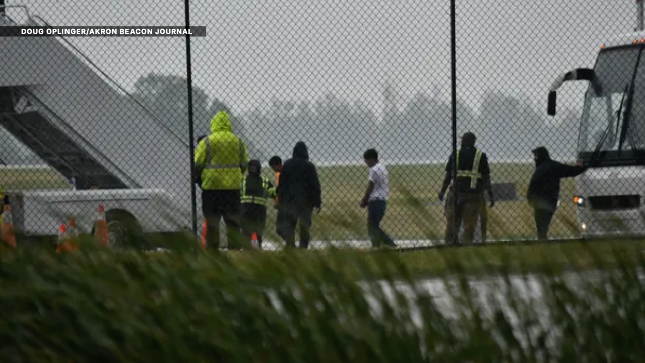 Detainees with their hands bound leave an unmarked white bus at the AVFlight facility at Akron-Canton Airport July 21 and board an Eastern Air jet bearing the tail number N668CP. (Photos taken from West Airport Drive through a chainlink fence.) Doug Oplinger, Special To The Akron Beacon Journal