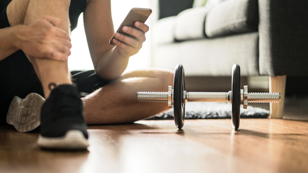 Man,Using,Smartphone,During,Workout,At,Home.,Online,Personal,Trainer