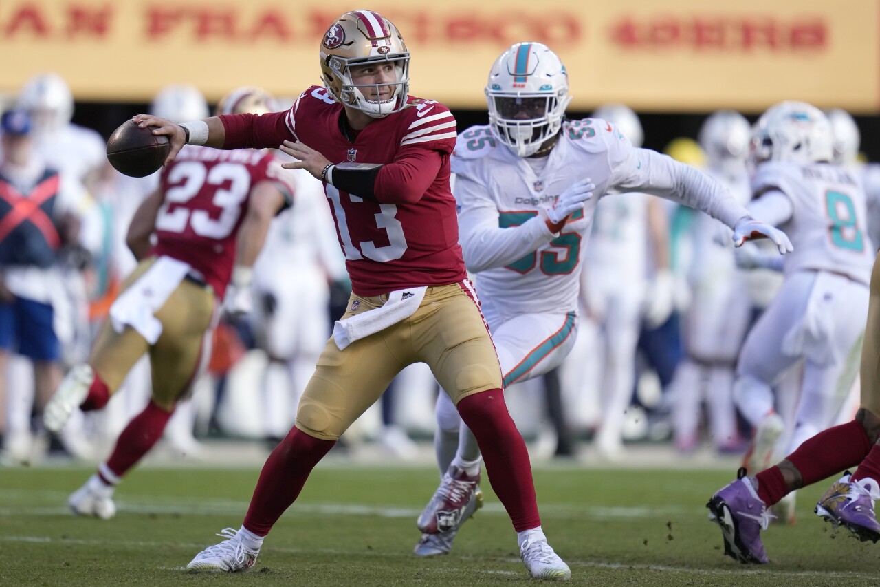 San Francisco 49ers QB Brock Purdy throws as Miami Dolphins linebacker Jerome Baker runs at him, Dec. 4, 2022