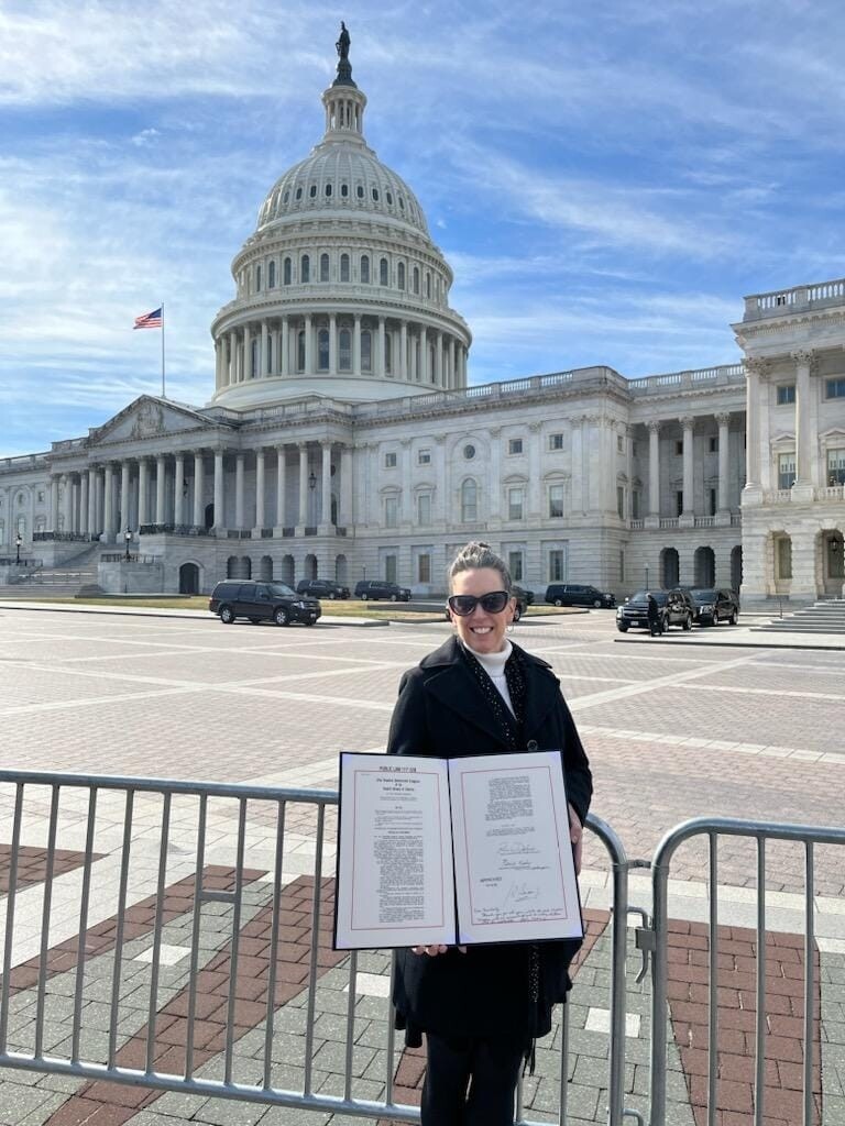 kim with signed bill in front of capitol.jpg