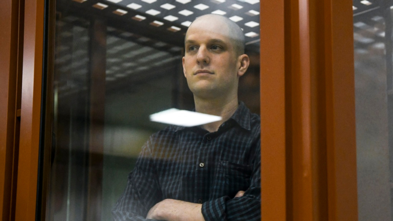 Wall Street Journal reporter Evan Gershkovich stands in a glass cage in a courtroom