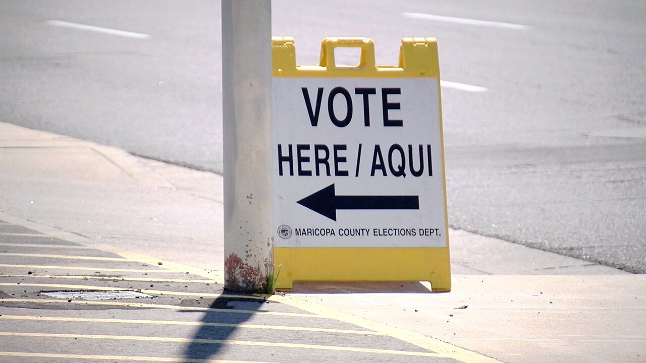 A "vote here/aqui" sign sits on a sidewalk in Maricopa County.