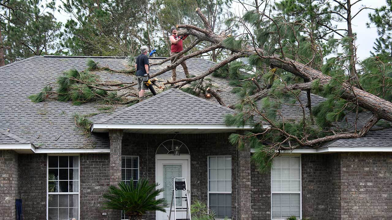 Jeff Lundy cuts up a pine tree that fell on his father-in-law's house during Isaias on Saturday, Oct. 10, 2026, in Milton, Fla. (AP Photo/Octavio Jones)