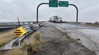 A photo of the scene taken by FOX 13's Sean Moody. It's a daytime, the sky is cloudy, and the metal barrier ahead of the exit leading to Salt Lake City International Airport is damaged. Asphalt is scattered about the road.