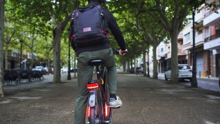 Man,Commuting,On,Electric,Bicycle,Through,Green,City,Street