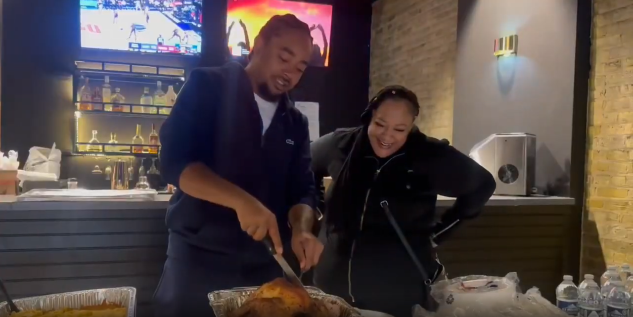 Dontay White (left) cuts into a turkey during a free Thanksgiving meal giveaway at King's Kitchen & Cocktails on Saturday, Nov. 22, 2025 in Racine.