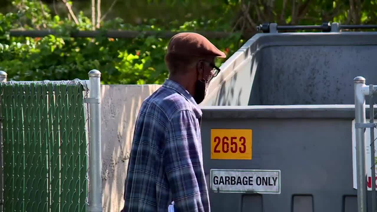 Robert Adams stands by dumpster and sign that reads 'Garbage Only'