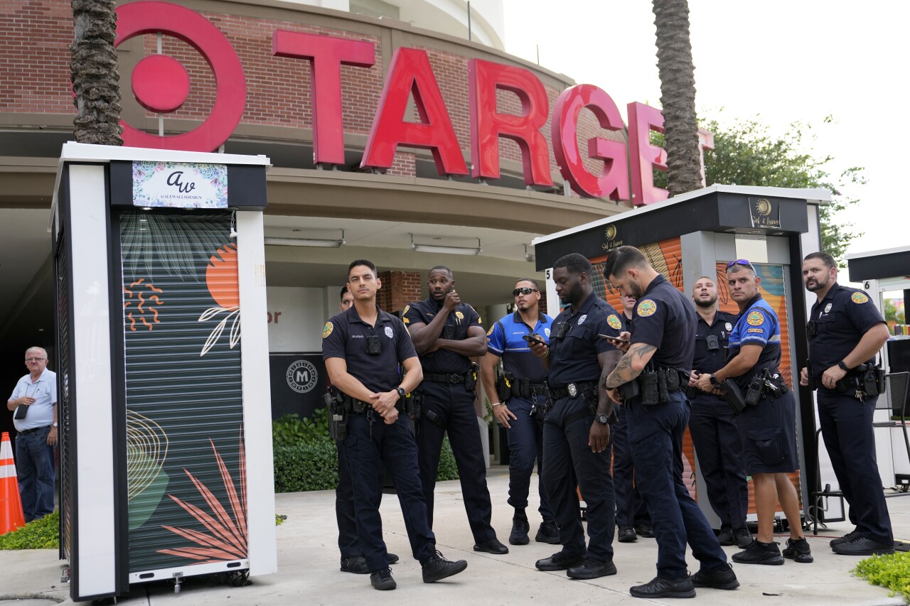 Police officers stand outside of a Target store as a group of people across the street protest against Pride displays.