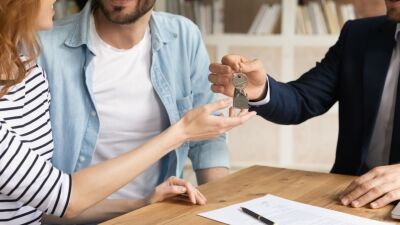 A real estate agent hands over a set of keys to a homebuyer.