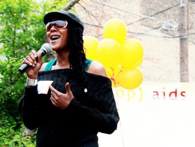 Jennie Wright speaks into a microphone on a sunny day in an undated photo. She is wearing a black cap and sunglasses, and yellow balloons appear in the photo behind her.