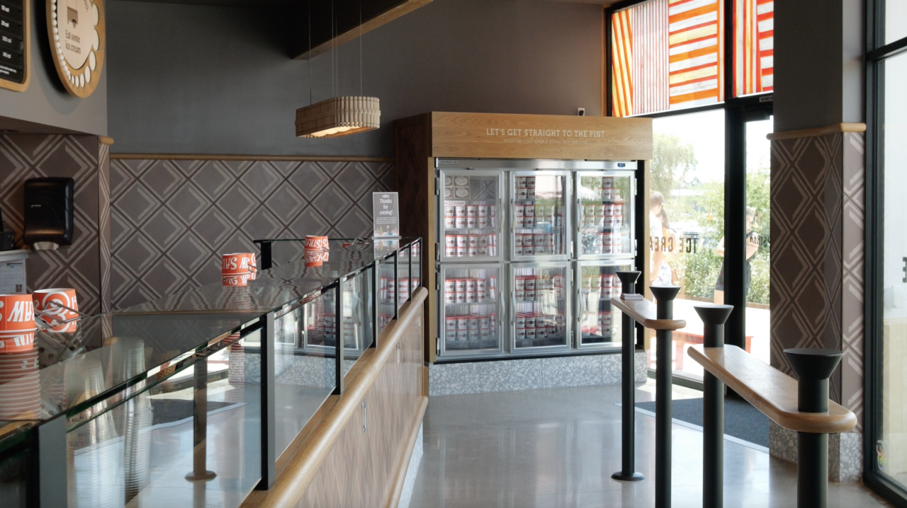 Ice cream shop area that features freezer with 'Let's get straight to the pint' quote.