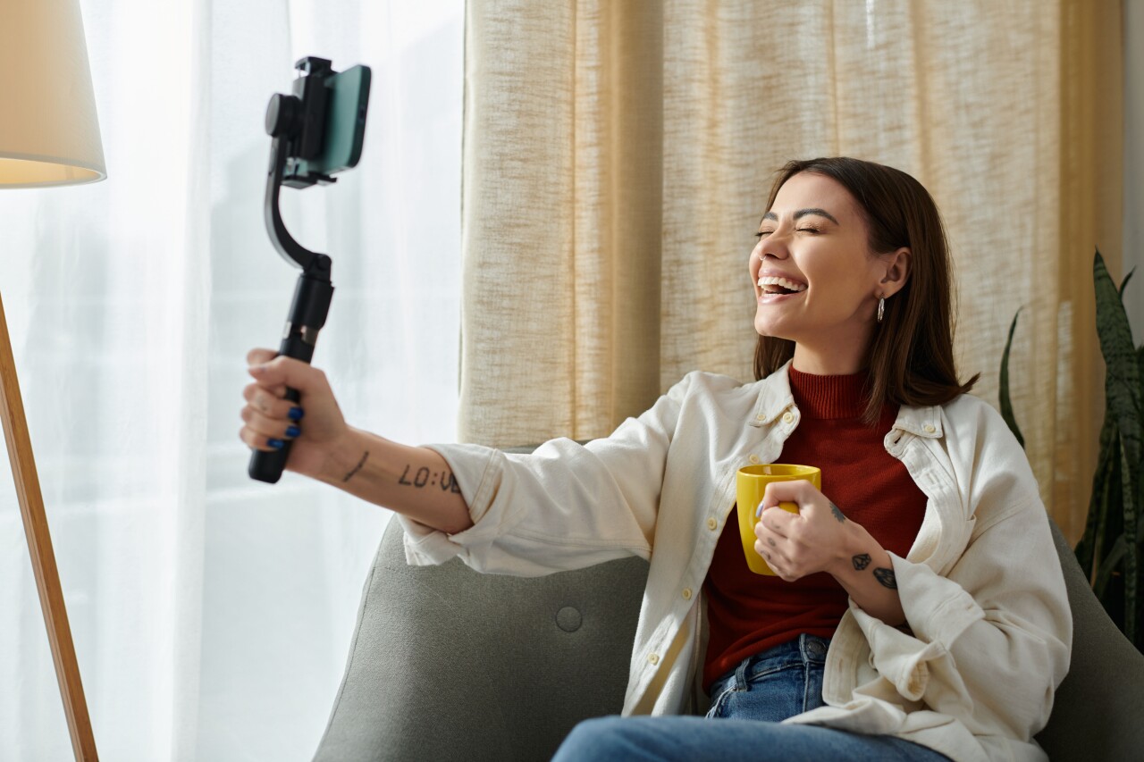 An influencer with tattoos and a cup of coffee creating a video.