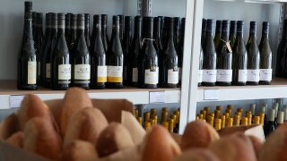 Baguettes are shown in front of wines from France displayed at Galinette, a French bistro, in San Francisco, Friday, March 14, 2025.