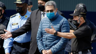 Former Honduran President Juan Orlando Hernandez, second from right, is taken in handcuffs to a waiting aircraft as he is extradited to the United States, at an Air Force base in Tegucigalpa, Honduras, April 21, 2022. 