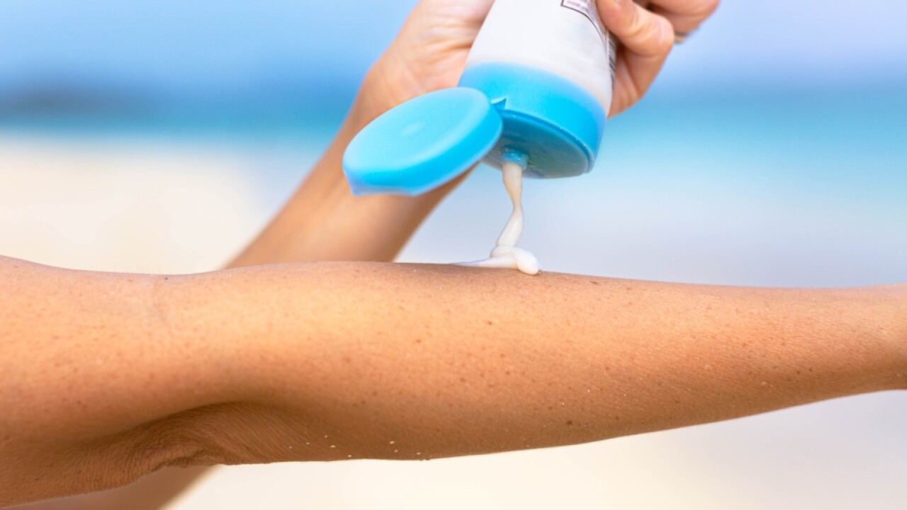 A person applying sunscreen on their arm.
