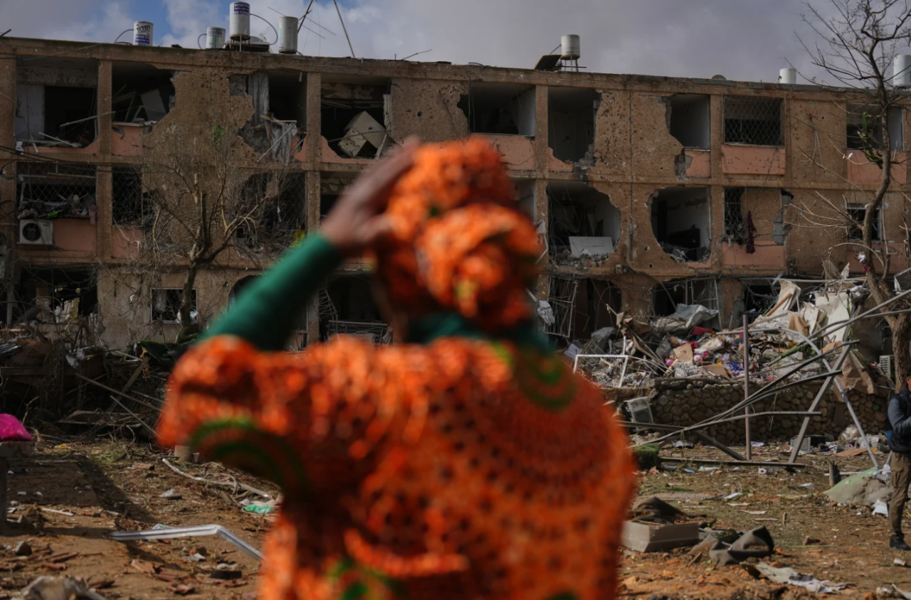 People survey a site that was struck by an Iranian missile in Dimona, southern Israel, Sunday, March 22, 2026.