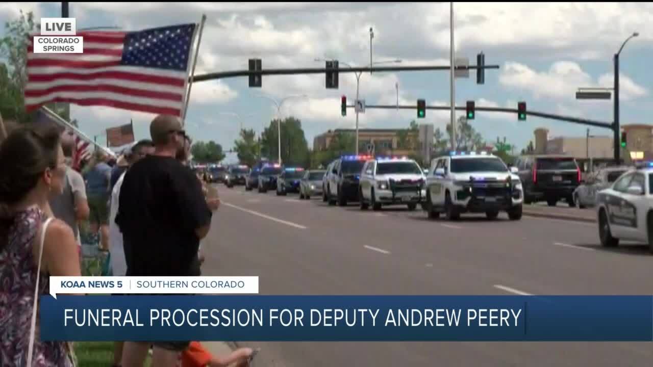 Bystanders wave American Flags in honor of fallen deputy Andrew Peery