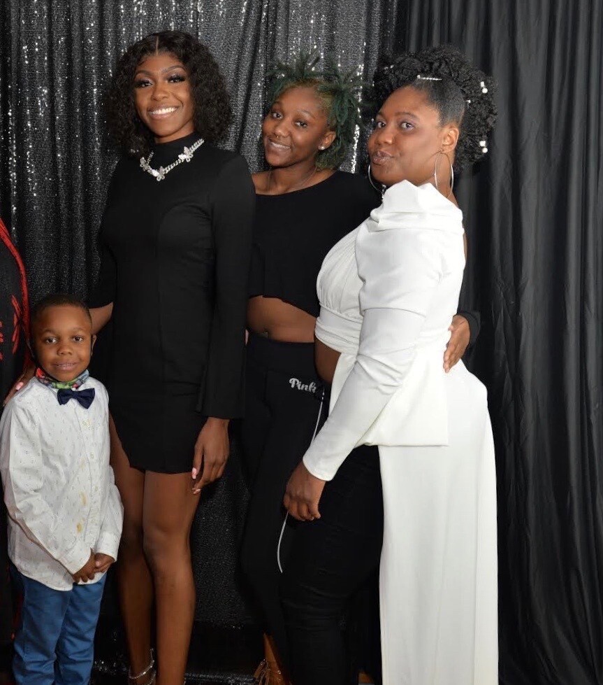 LaTasha Hambrick, far right, poses with her two daughters and her son in an undated family photo. Hambrick is wearing a white top with braids pulled up into a bun.