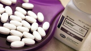 Lipitor tablets in a purple tray next to an open medicine bottle